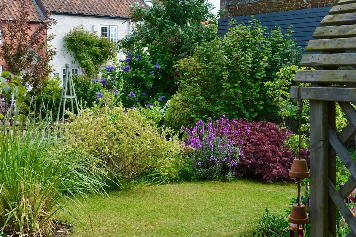 Frodig blomsterhage med fargerike blomster foran et hus